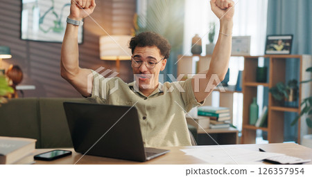 Man, laptop and fist pump with celebration in home with goal, winning or documents for investment. Person, computer and happy for success with achievement, profit or revenue with trading at apartment 126357954