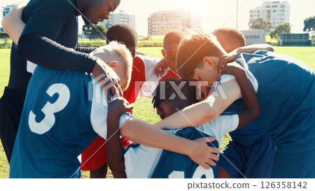 Huddle, soccer and coach with group of children on field for motivation, game plan and strategy. Competition, training and practice with kids outdoor for youth sports, football player and support 126358142