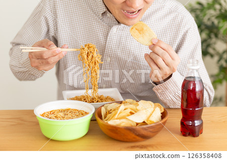 Middle-aged man binge eating junk food 126358408