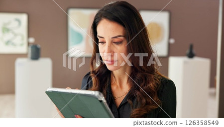 Creative, woman and reading on tablet at gallery for research, artwork information and schedule event. Female curator, digital and social media reviews, online auction and art catalog for exhibition 126358549