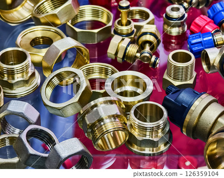 Display of various brass plumbing fittings and connectors arranged on a glossy surface in a hardware store 126359104
