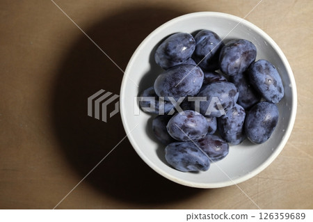 Ceramic bowl full of raw fresh blue plums. Ceramic bowl full of raw fresh blue plums. 126359689