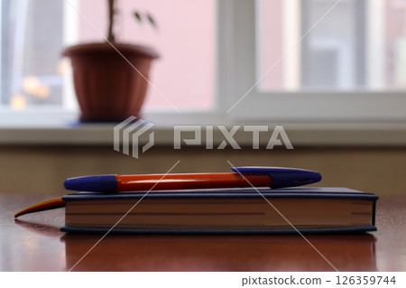 Workplace near a window with a notebook and a pen. Workplace near a window with a notebook and a pen. 126359744