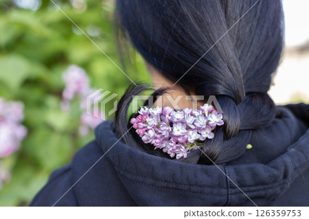 Dark haired girl with lilac flowers on her hair. Rear view. Closeup. 126359753