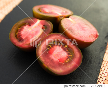 Black halves of tomatoes on black stone board Black halves of tomatoes on black stone board 126359918