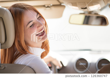 Young redhead woman driver driving a car smiling happily. Young redhead woman driver driving a car smiling happily. 126360747