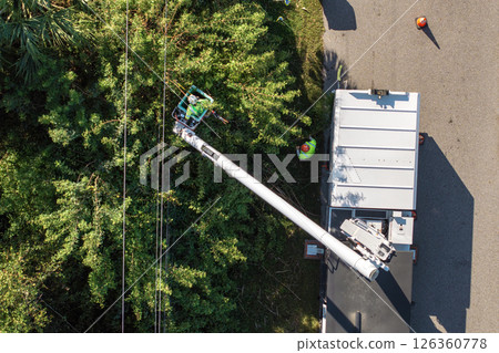 Worker in lift truck trimming tree around power lines. Maintenance of electrical grid by city utility cervices Worker in lift truck trimming tree around power lines. Maintenance of electrical grid by city utility cervices 126360778
