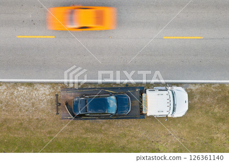Traffic accident with tow truck hauling smashed vehicle on car crash site. First responders helping on road emergency in Florida 126361140
