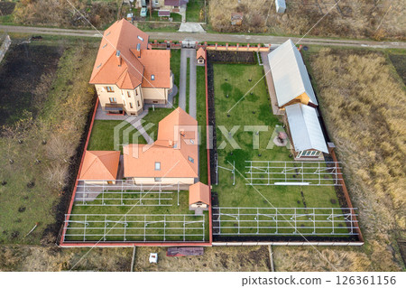 Top down aerial view of a private house with red tiled roof and frame structure prepared for installation of solar panels. 126361156