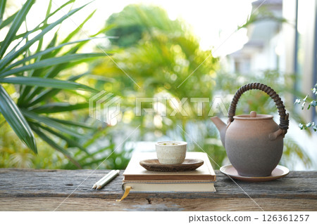 ancient tea pot and tea cup and notebook, cozy balcony workspace 126361257