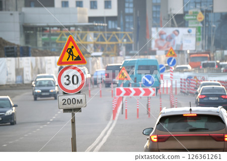 Roadworks warning traffic signs of construction work on city street and slowly moving cars 126361261