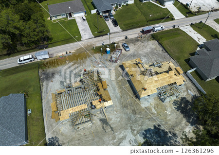 Professional builders working on roof construction of unfinished suburban home with wooden frame structure in Florida rural area. Concept of housing development in America 126361296