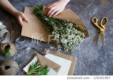 Creating a rustic floral arrangement with natural materials on a textured surface in a cozy crafting space Creating a rustic floral arrangement with natural materials on a textured surface in a cozy crafting space 126361967