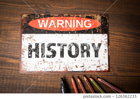 History Concept. Warning Sign on Vintage Background with Colored Pencils and Marker on Wooden Table 126362235