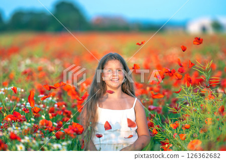 cute girl wearing white dress in summer blooming poppy field playing under evening sun cute girl wearing white dress in summer blooming poppy field playing under evening sun 126362682
