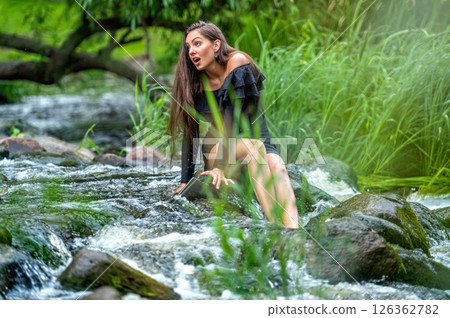 female freelancer sitting on a rock in the river and dropping her laptop into the water female freelancer sitting on a rock in the river and dropping her laptop into the water 126362782