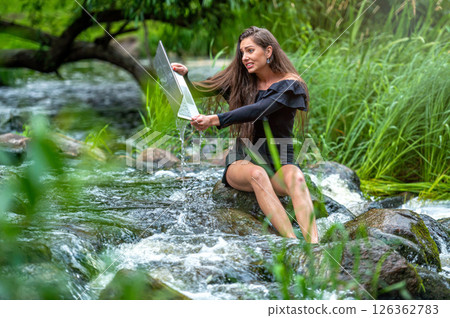 worried woman pulls out of water laptop that fell into river, remote holiday work accident 126362783