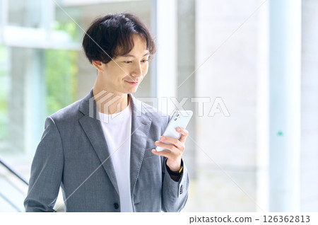 Business casual male engineer operating a smartphone in the office Business casual male engineer operating a smartphone in the office 126362813