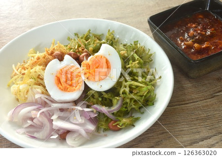 spicy and sour slice wing bean and banana blossom with chop pork sauce topping boiled egg Thai salad on plate 126363020