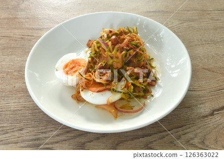 spicy and sour slice wing bean and banana blossom with chop pork sauce topping boiled egg Thai salad on plate spicy and sour slice wing bean and banana blossom with chop pork sauce topping boiled egg Thai salad on plate 126363022