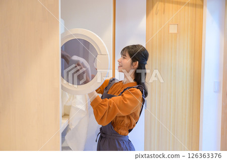 A smiling Japanese woman doing laundry 126363376