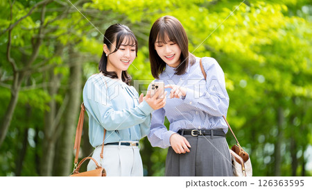 Two women/businesswomen talking while looking at smartphones 126363595