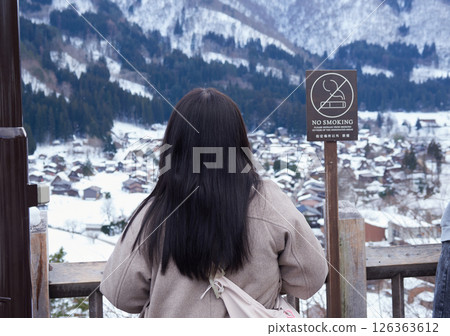 A female tourist at the observation deck of Shirakawa-go in winter and the Gassho Village scenery A female tourist at the observation deck of Shirakawa-go in winter and the Gassho Village scenery 126363612
