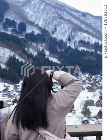 A female tourist at the observation deck of Shirakawa-go in winter and the Gassho Village scenery A female tourist at the observation deck of Shirakawa-go in winter and the Gassho Village scenery 126363613