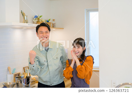 一位日本男子和一位身著工作服的家庭主婦並肩站在廚房裡 一位日本男子和一位身著工作服的家庭主婦並肩站在廚房裡 126363721