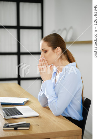 Business woman deep in thought at her workspace in a modern office setting 126363946