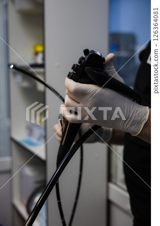 A veterinarian wearing surgical gloves carefully holds and prepares an endoscope for a medical procedure, demonstrating precision and care in animal care. An endoscope in the hands of a veterinarian. 126364081