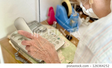 Elderly woman's hand holding a landline telephone receiver Elderly woman's hand holding a landline telephone receiver 126364252