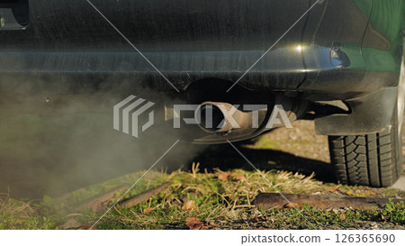A close-up of a car exhaust pipe, from which a large cloud of dark smoke is coming out. Probloms of global warming due to greenhouse gases. A close-up of a car exhaust pipe, from which a large cloud of dark smoke is coming out. Probloms of global warming due to greenhouse gases. 126365690