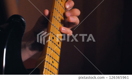 Close-up of a maple electric guitar fingerboard with vintage-style dot overlays. Guitarist's fingers press the strings to the fret. Rock, honky tonk or jazz music. Close-up of a maple electric guitar fingerboard with vintage-style dot overlays. Guitarist's fingers press the strings to the fret. Rock, honky tonk or jazz music. 126365961