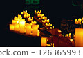 A close-up of a double bass and a piano surrounded by numerous lit candles. The background is blurred and orange. 126365993