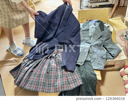 Elderly woman's hand holding a female student's uniform 126366016