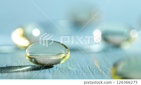 Softgels and fish oil, vitamin D capsules reflecting light against a blue background, creating a stunning bokeh effect while highlighting the importance of health and wellness in daily nutrition 126366275