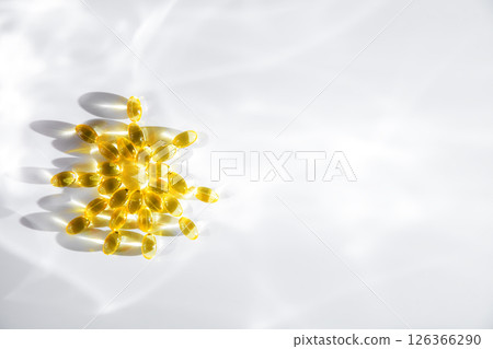 vitamin D or Fish oil yellow transparent capsules forming a sun shape on a white background, emphasizing themes of health, wellness, and nutrition vitamin D or Fish oil yellow transparent capsules forming a sun shape on a white background, emphasizing themes of health, wellness, and nutrition 126366290
