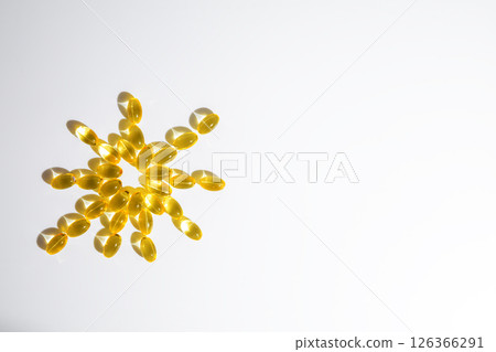 vitamin D or Fish oil yellow transparent capsules forming a sun shape on a white background, emphasizing themes of health, wellness, and nutrition vitamin D or Fish oil yellow transparent capsules forming a sun shape on a white background, emphasizing themes of health, wellness, and nutrition 126366291