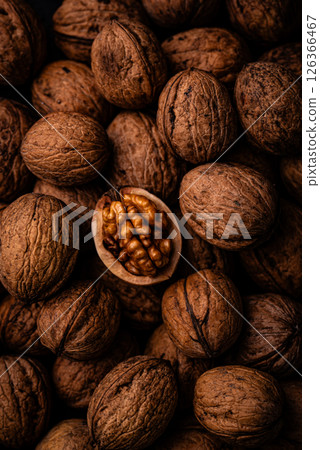 Pile of walnuts with one opened, showcasing texture 126366467