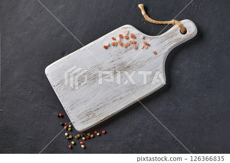 white cutting board with sprinkled pink salt and colorful peppercorns on black stone table 126366835