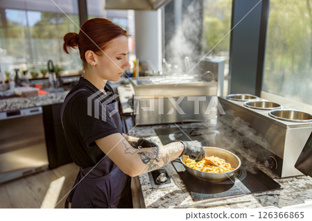 A skilled chef is expertly preparing vibrant and delicious pasta dishes in a modern kitchen A skilled chef is expertly preparing vibrant and delicious pasta dishes in a modern kitchen 126366865