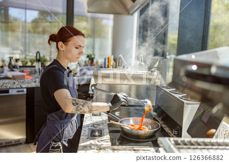 A skilled chef is expertly cooking delicious dishes in a modern, stateoftheart kitchen 126366882