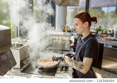 A talented chef skillfully cooking in a modern kitchen environment with great passion and artistry A talented chef skillfully cooking in a modern kitchen environment with great passion and artistry 126366884