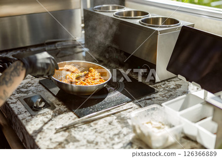 A Chef is Cooking in a Modern Kitchen Using Fresh Ingredients for Delicious Meals A Chef is Cooking in a Modern Kitchen Using Fresh Ingredients for Delicious Meals 126366889