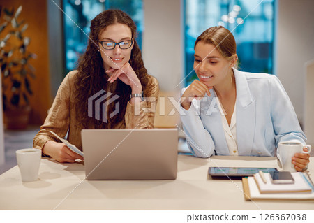 In a modern office, two professionals collaborate on a laptop to achieve their goals 126367038