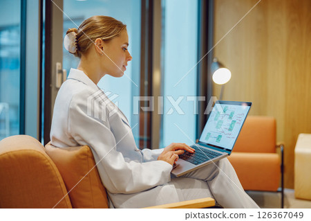 A Focused Professional Diligently Working on a Laptop in a Modern Office Setting Environment 126367049