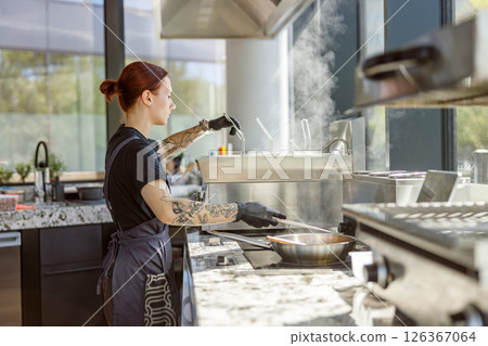 A Chef is Busy Preparing a Gourmet Dish in a Contemporary Modern Kitchen Environment A Chef is Busy Preparing a Gourmet Dish in a Contemporary Modern Kitchen Environment 126367064
