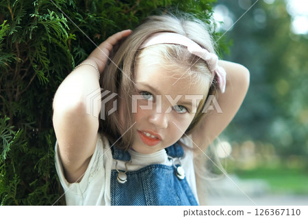 Portrait of happy pretty child girl standing in summer park looking in camera. Portrait of happy pretty child girl standing in summer park looking in camera. 126367110