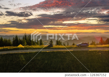 Offroad camping site on hillside at bright sunset. SUV vehicle and tent shelters on mountain campsite on sunny evening. Active tourism and hiking concept Offroad camping site on hillside at bright sunset. SUV vehicle and tent shelters on mountain campsite on sunny evening. Active tourism and hiking concept 126367152